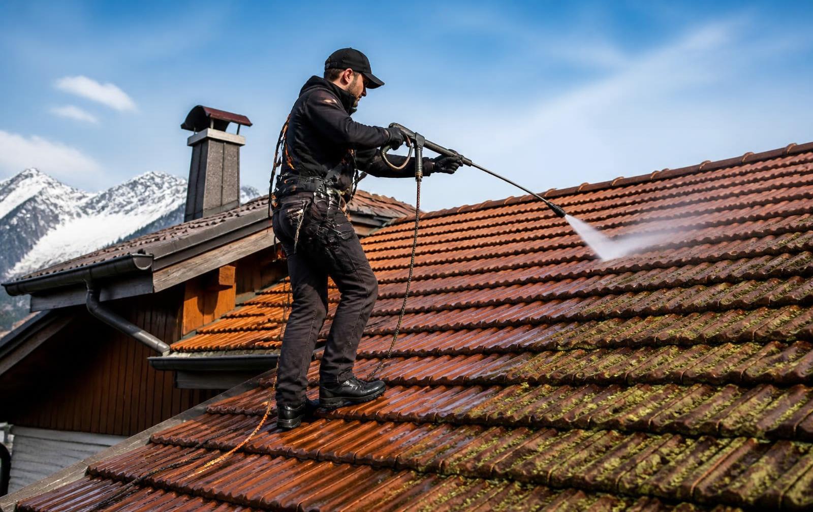 Artisan D.F NETTOYAGE démoussant une toiture en tuiles au nettoyeur haute pression